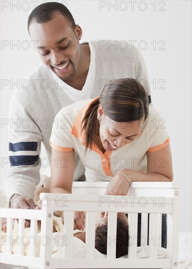 African couple looking at baby in crib