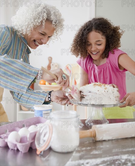 Grandmother and granddaughter frosting cake