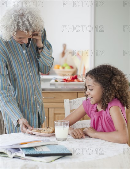 Grandmother serving granddaughter cookies