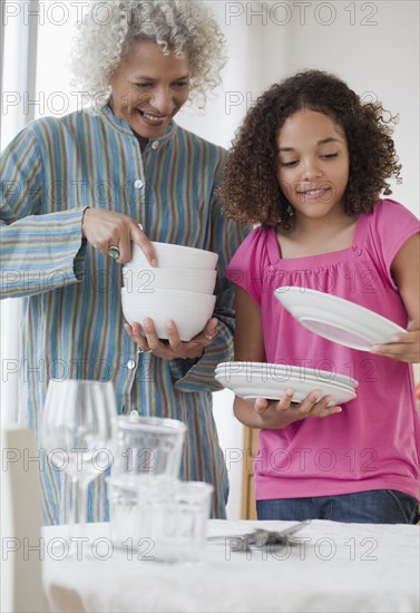 Grandmother and granddaughter setting table