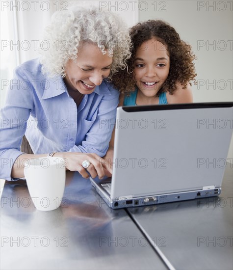 Grandmother and granddaughter using laptop