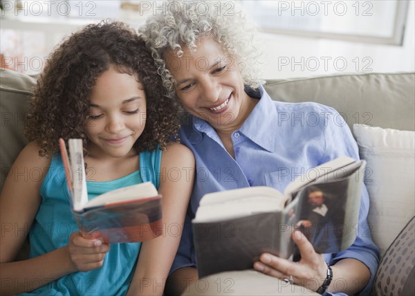 Grandmother and granddaughter reading on sofa