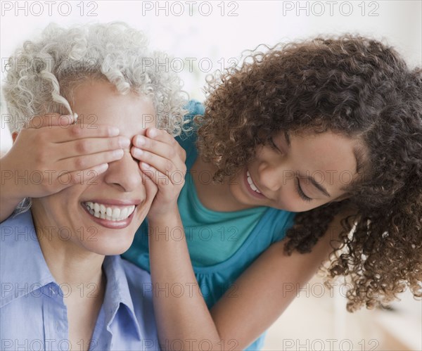 Granddaughter covering grandmother's eyes