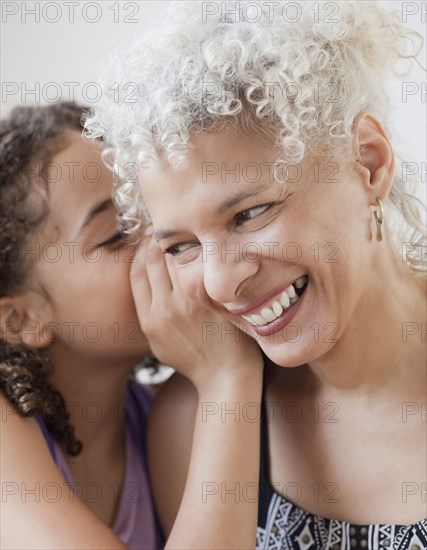 Granddaughter whispering into grandmother's ear