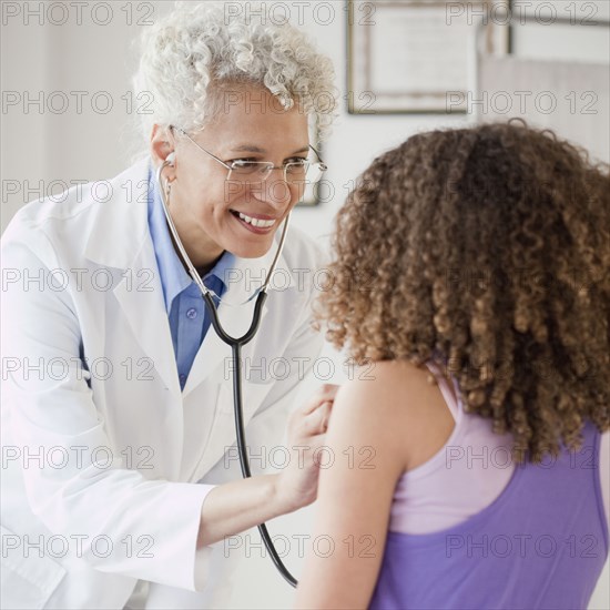 Doctor checking girl's heart with stethoscope