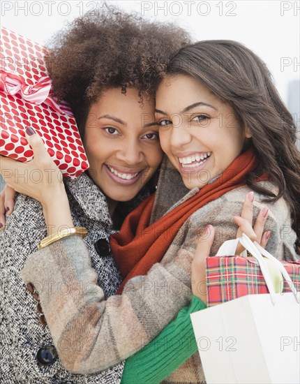 Friends hugging and holding Christmas gifts