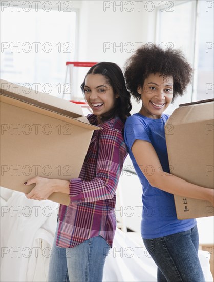 Friends carrying cardboard moving boxes