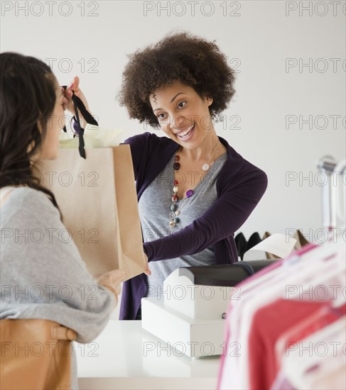 Sales clerk handing customer shopping bag