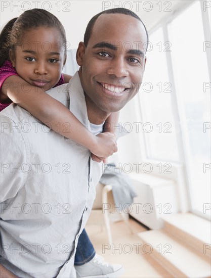 African American father carrying daughter on back