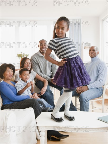 African American family watching daughter standing on table