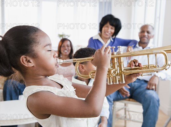 African American family watching daughter play trumpet