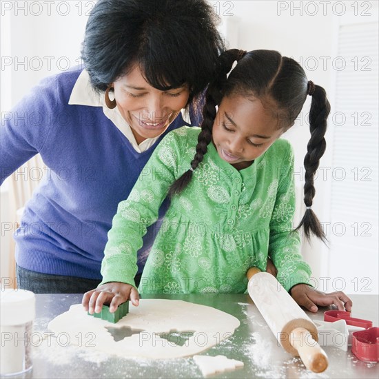 Black grandmother baking cookies with granddaughter