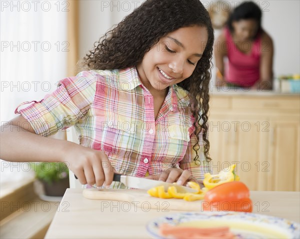 Mixed race girl cutting bell peppers