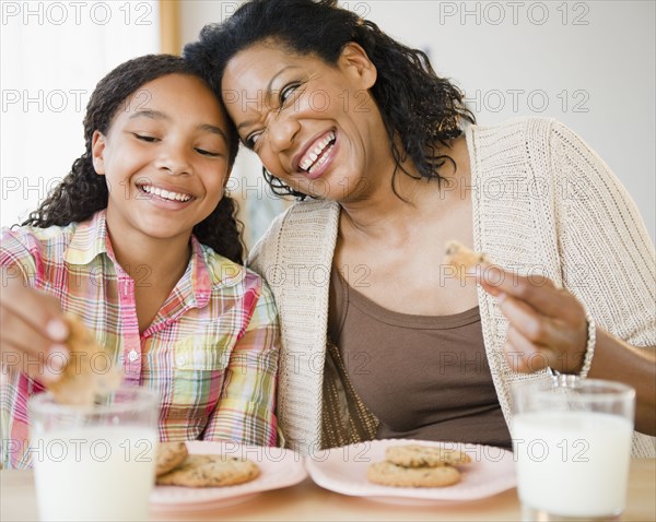 Mother and daughter eating cookies and milk together