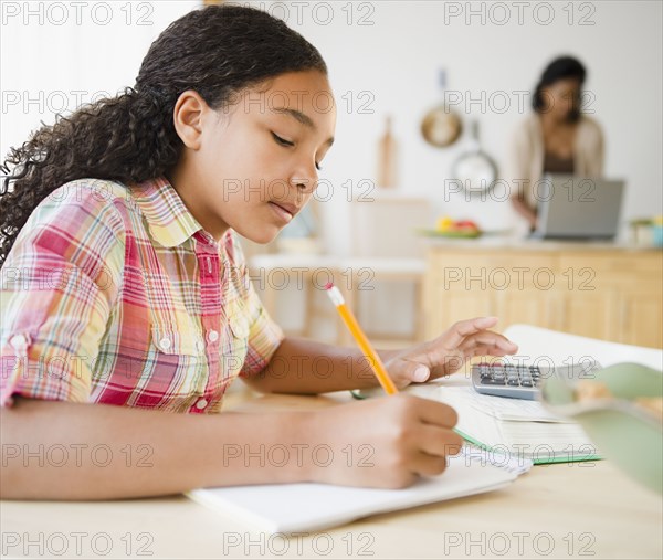 Mixed race girl doing homework in kitchen