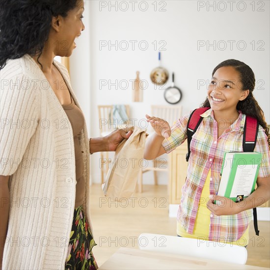 Mother handing daughter paper bag lunch