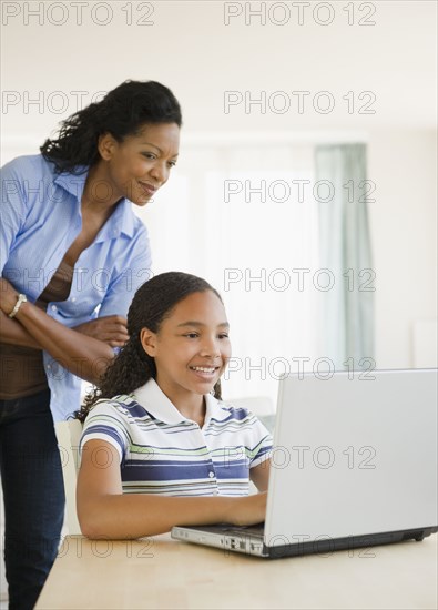 Mother watching daughter using laptop