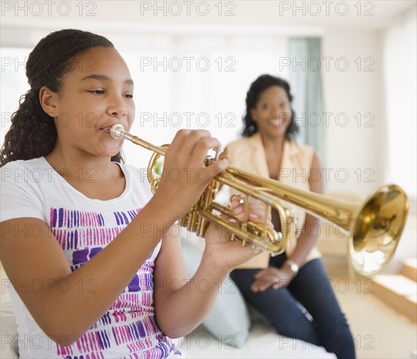 Mother watching daughter playing trumpet