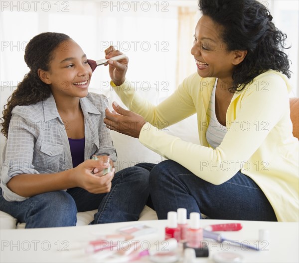 Mother putting makeup on daughter