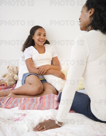 Mother and daughter talking in bed