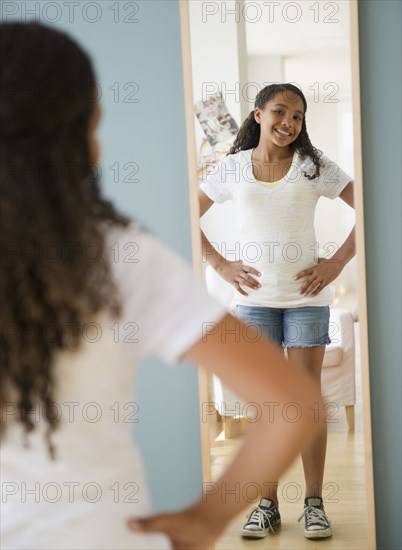 Mixed race girl checking reflection in mirror