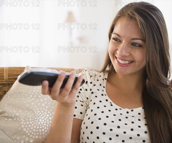 Smiling Indian woman using remote control