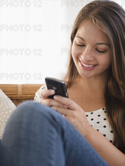 Smiling Indian woman text messaging on cell phone