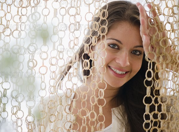 Smiling Indian woman behind modern curtain