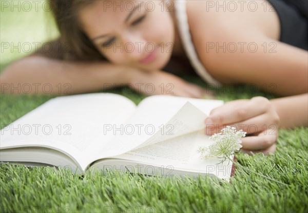 Indian woman laying in grass reading book