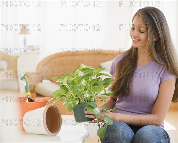 Indian woman putting house plant into pot