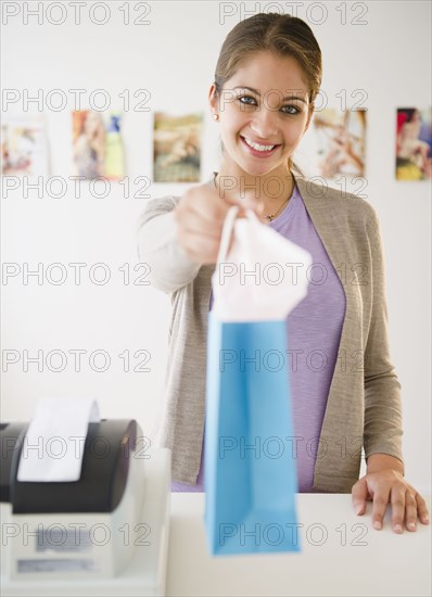 Indian shop clerk  handing over shopping bag