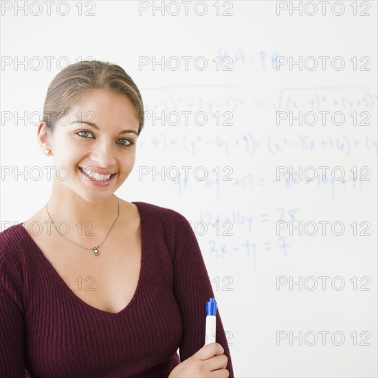Smiling Indian student next to whiteboard in classroom