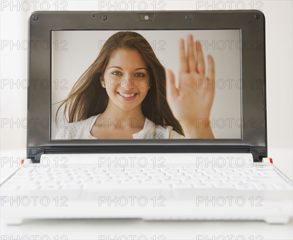 Indian woman waving from laptop display screen