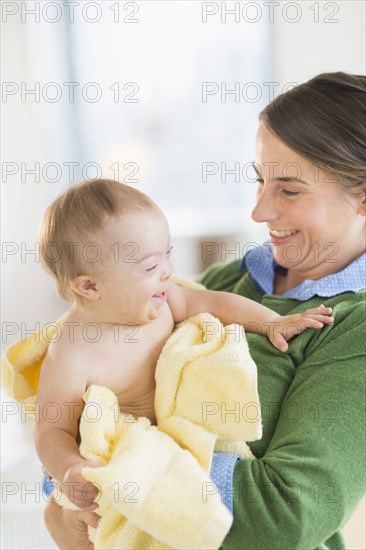 Caucasian mother toweling baby girl with Down Syndrome