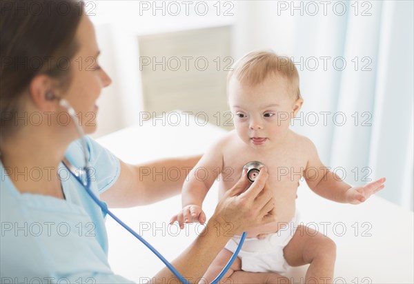 Caucasian doctor tending to baby girl with Down Syndrome
