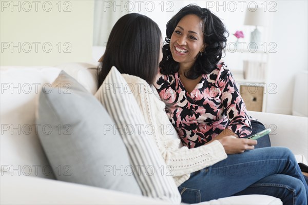 Mother and daughter talking on sofa with cell phone