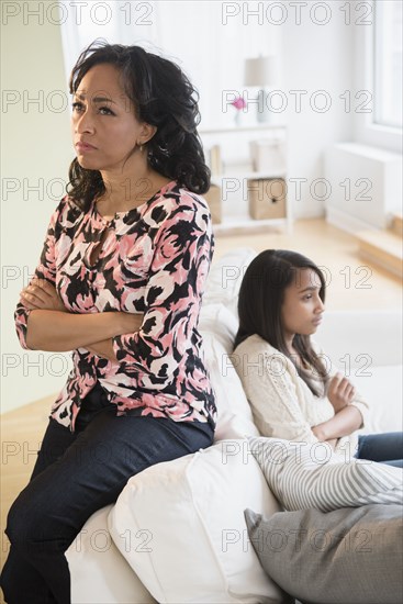 Frustrated mother and daughter sitting on sofa