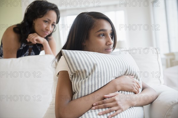 Mother watching pensive daughter clutching pillow