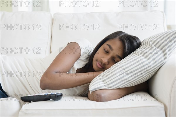 Mixed Race girl sleeping on sofa with pillow