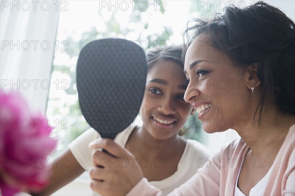 Mother and daughter looking in handheld mirror