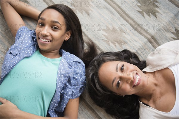 Smiling mother and daughter laying on carpet