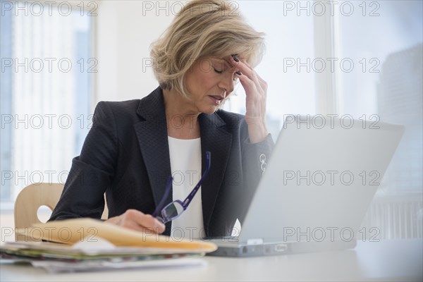 Caucasian businesswoman with headache using laptop