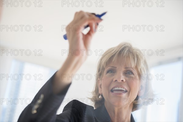 Caucasian businesswoman writing on glass wall