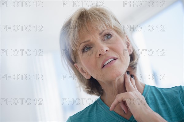 Older Caucasian woman checking pulse on neck