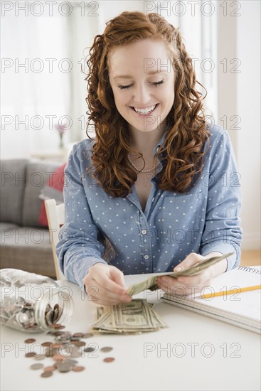 Caucasian woman counting money from savings jar