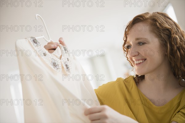 Smiling Caucasian woman holding blouse on coathanger