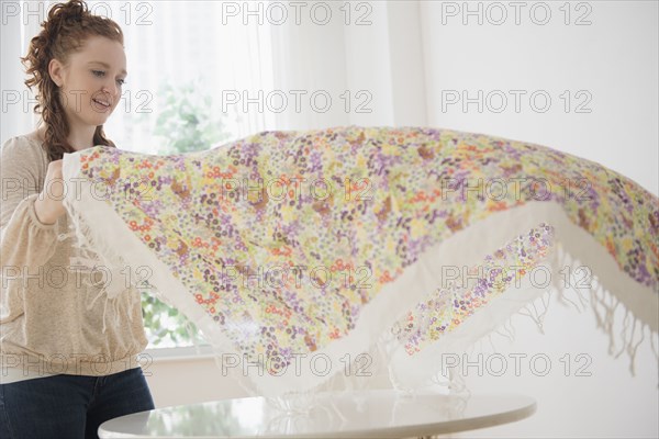 Caucasian woman placing tablecloth on table