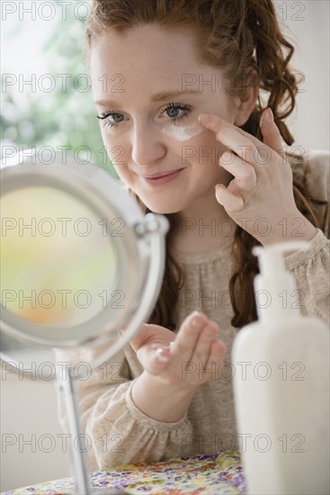 Caucasian woman applying moisturizer to face