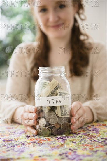 Caucasian woman showing money in tip jar