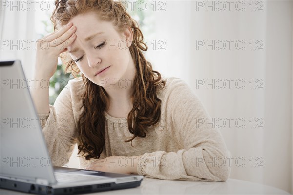 Caucasian women using laptop rubbing forehead